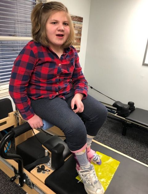 Child with adaptive equipment on a Pilates Reformer.