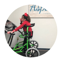 A young female patient uses a custom mobility aid during physical therapy.