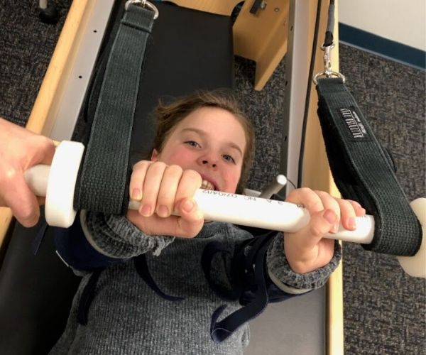 Child in the middle of Pilates reformer therapy.