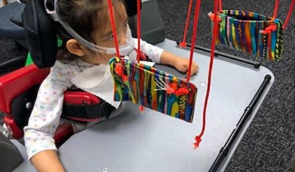 Child using a custom tool during a pediatric physical therapy session.