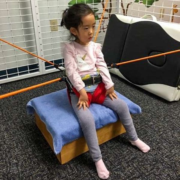 Child using a Universal Exercise Unit during a physical therapy session.